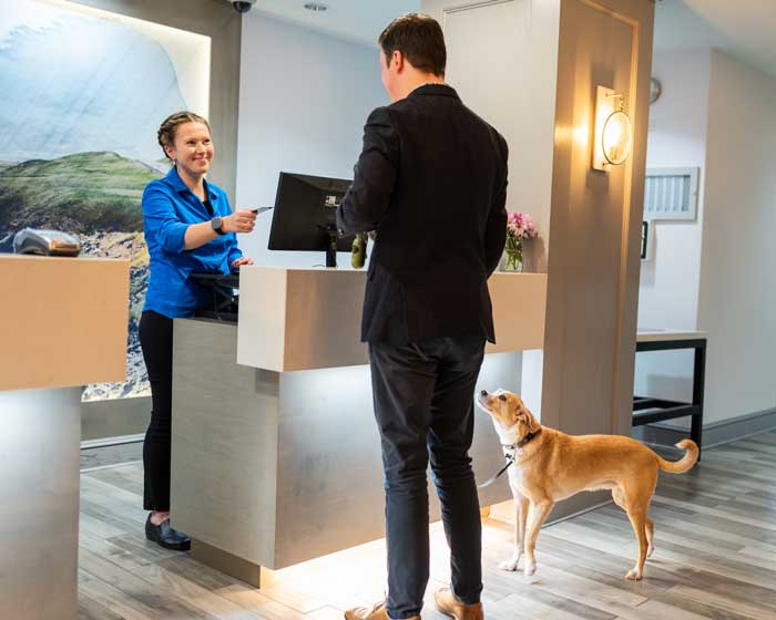 person checking in at front desk with pet, link to amenities