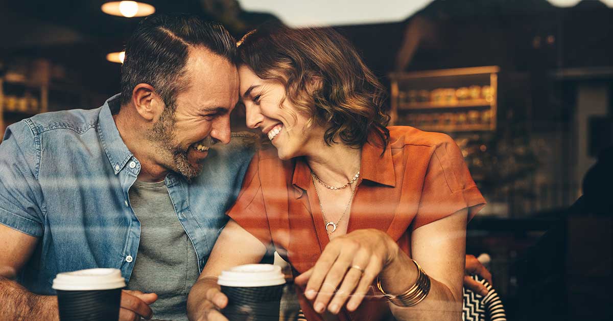 Beautiful couple in love at a cafe with a disposable coffee cup each