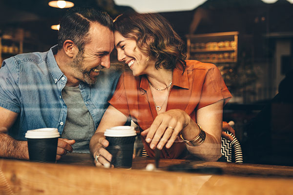 Beautiful couple in love at a cafe with a disposable coffee cup each