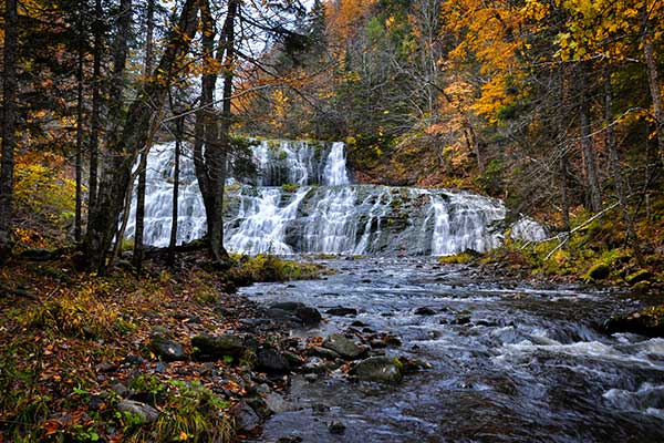 A two-tier waterfall in Margaree, Nova Scotia during fall colours.