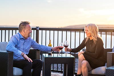 Man and woman enjoying drinks on The Simon Sydney rooftop patio